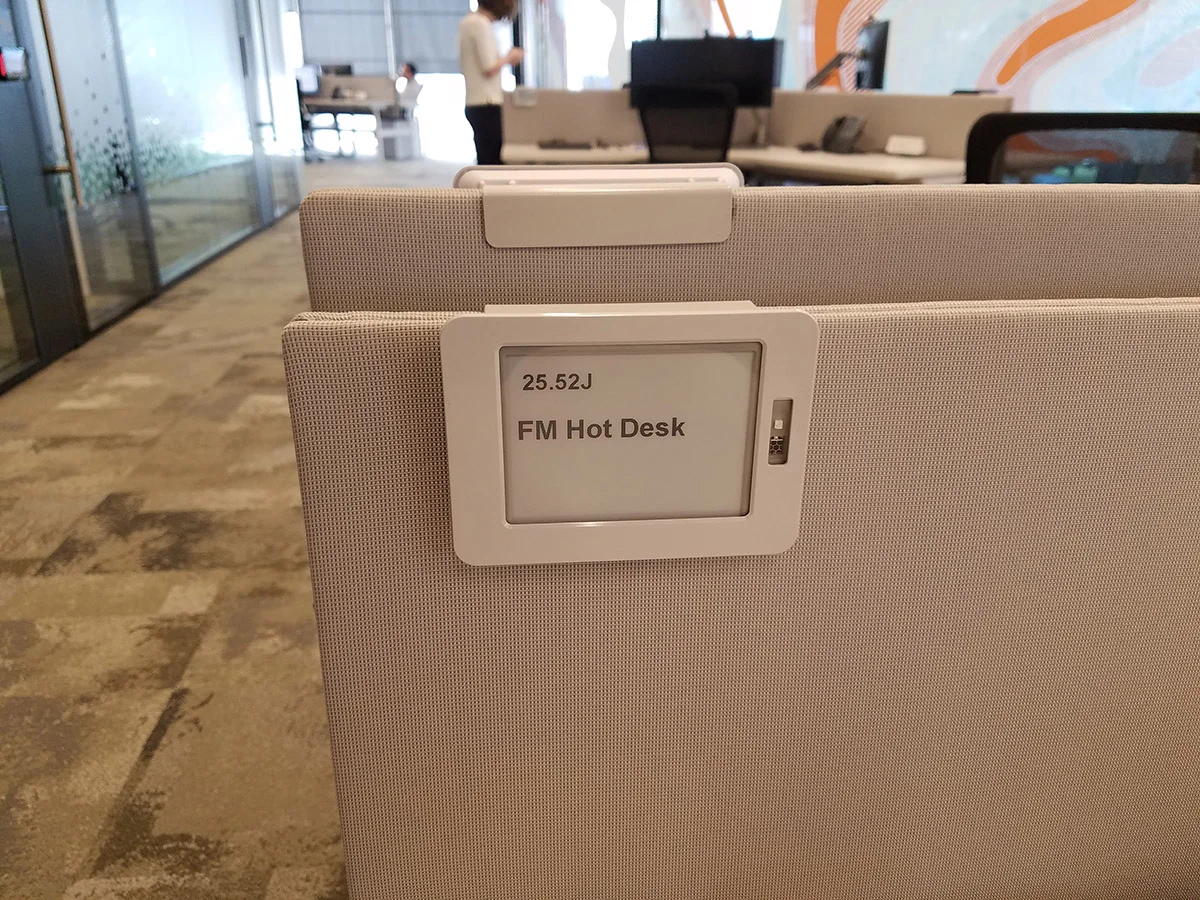 Office hot desk workspace with digital desk label and modern office interior