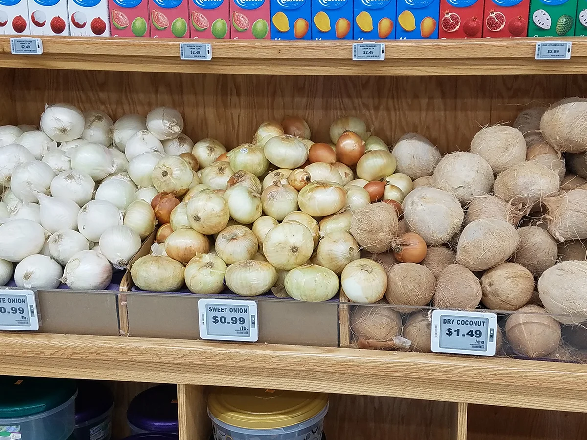 Vegetable section with onions and dry coconuts with price tags