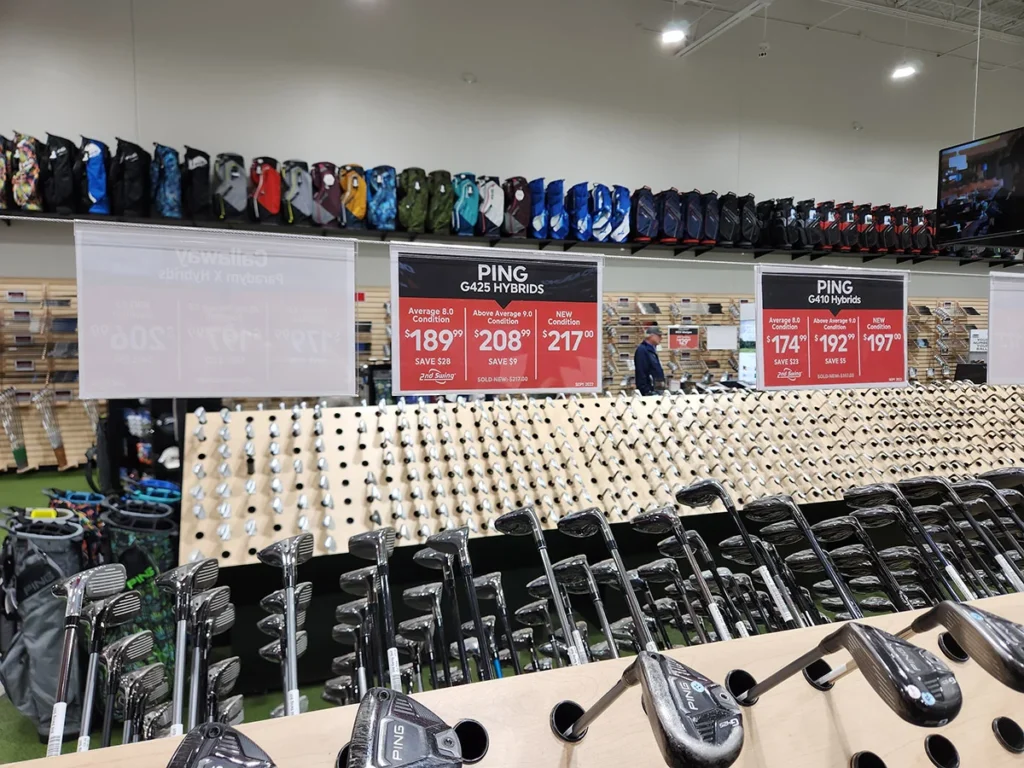 Golf equipment store display with irons, hybrids, and golf bags on shelves
