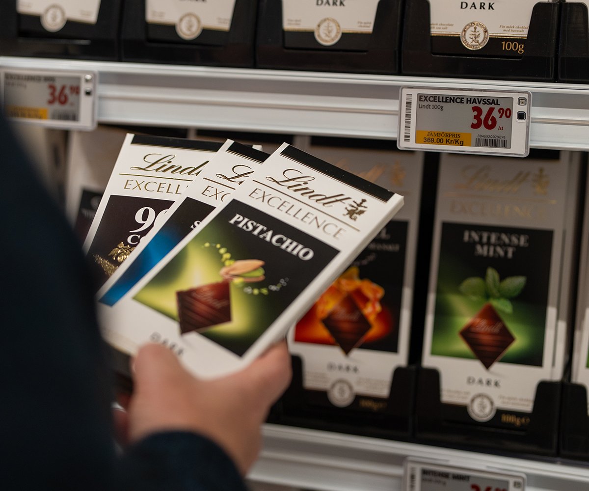Hand selecting Lindt Excellence chocolate bars from a store shelf