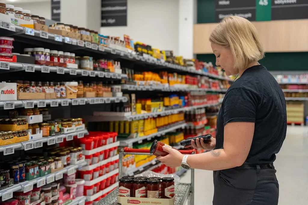 Store employee scanning grocery products on shelf with handheld barcode scanner in supermarket aisle